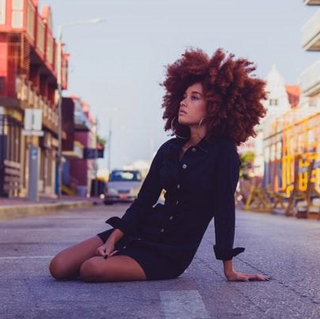 Lady with curly hair sitting in road